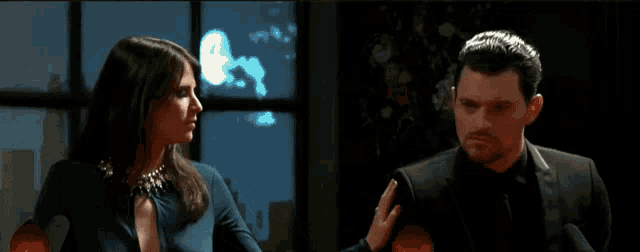 a man and a woman are sitting in front of a window at night