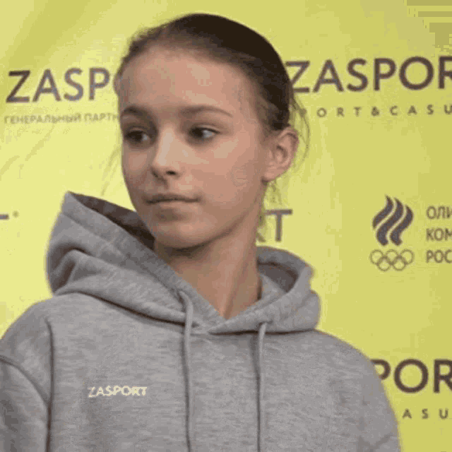 a girl wearing a gray hoodie with the word zasport on it