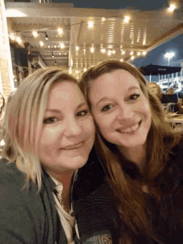 two women posing for a picture and one has a tattoo on her arm