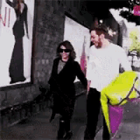 a man and a woman are standing next to each other on the sidewalk .