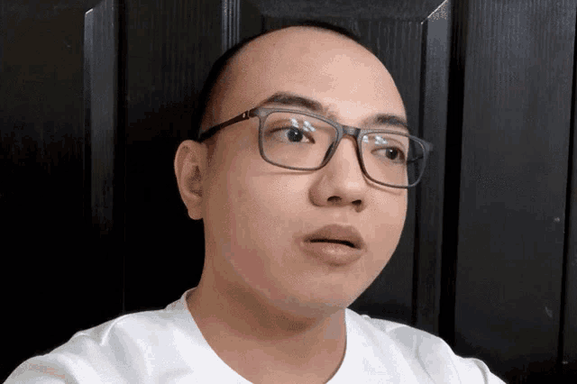 a man wearing glasses and a white shirt is looking at the camera