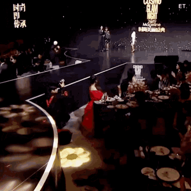 a woman in a red dress sits at a table in front of a sign that says cosmo glam night magazine