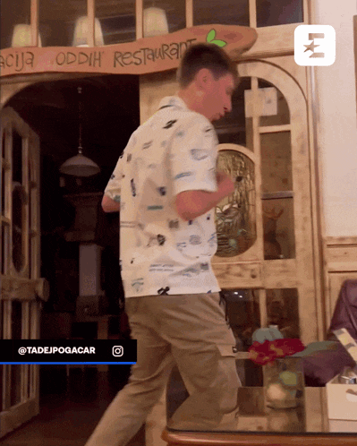 a man stands in front of a wooden sign that says oddih restaurant