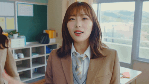 a woman in a suit and tie stands in a classroom