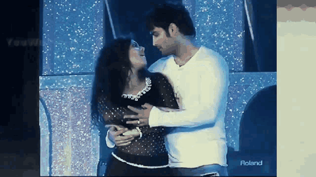 a man and a woman are dancing in front of a roland advertisement
