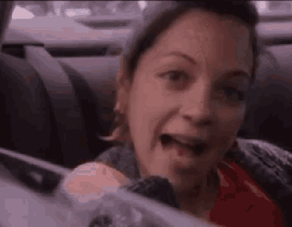 a woman is sitting in the back seat of a car with her mouth open and her tongue out .