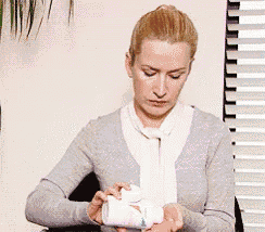 a woman in a grey sweater is holding a white bottle