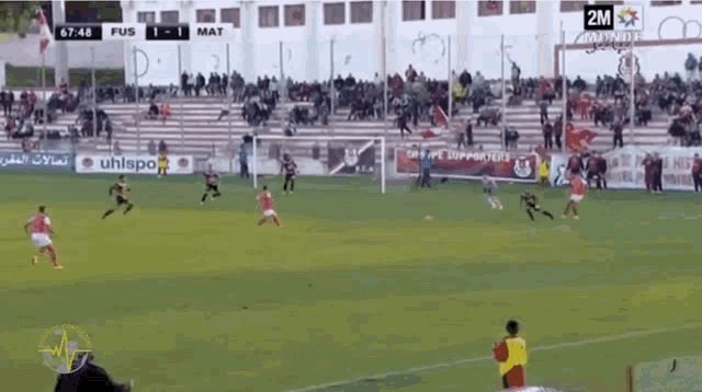 a soccer game is being played on a field with a sign that says uhlsport in the background
