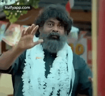 a man with a beard is wearing a lei around his neck and waving .