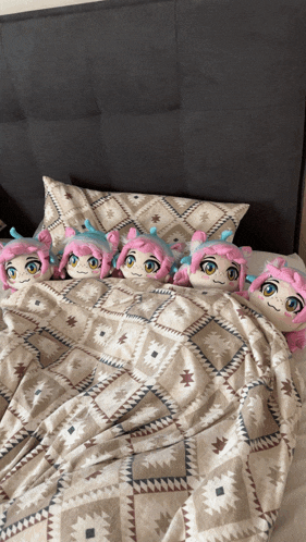 a bed with a patterned blanket and pillows with pink and blue stuffed animals on it