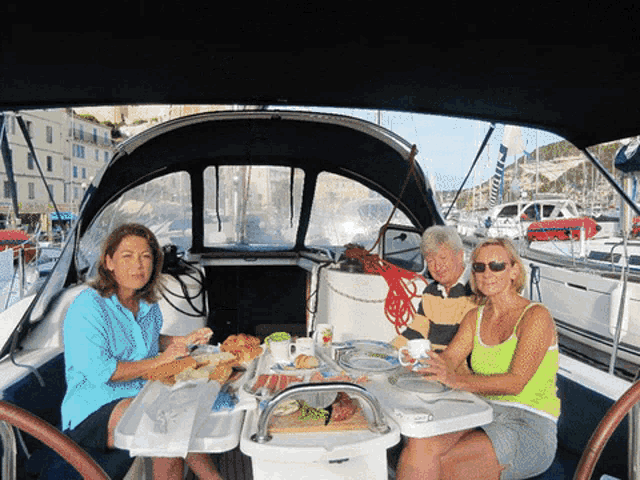 three women are sitting at a table on a boat eating