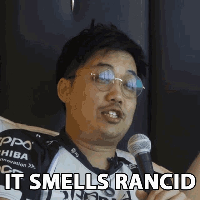 a man holding a microphone with the words " it smells rancid " above him