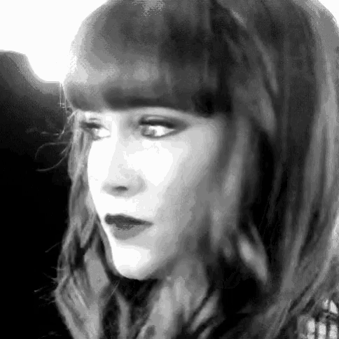 a black and white photo of a woman 's face with long hair and bangs .