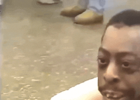 a man with a beard is sitting on the floor looking at the camera