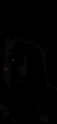 a man with a beard is making a funny face with his mouth open in the dark .