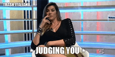 a woman is sitting in a chair with the words " judging you " on the screen