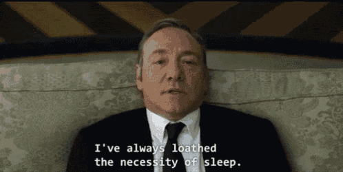 a man in a suit and tie is laying on a couch and says i 've always loathed sleep