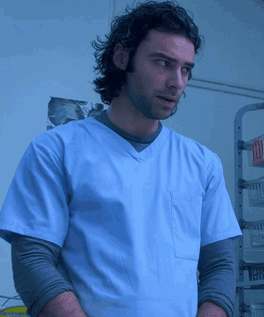 a man in a blue scrub top is standing in front of a shelf