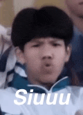 a young boy is making a funny face while sitting in a crowd .