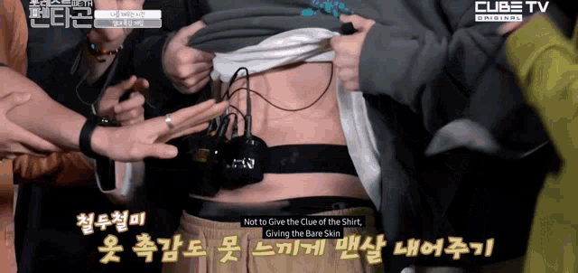 a group of people gathered around a person 's stomach with cube tv written on the bottom of the screen