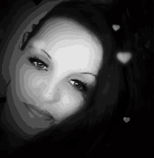 a woman 's face is shown in a black and white photo with hearts in the background