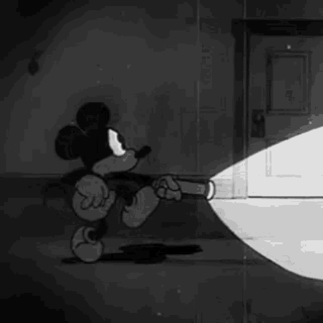 a black and white cartoon of mickey mouse holding a flashlight in his hand .