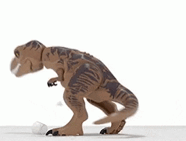 a toy dinosaur is standing on a white surface with its mouth open and a plastic bottle in its mouth .