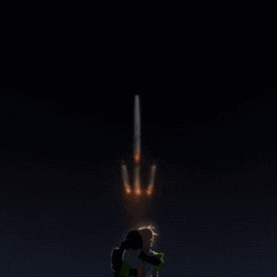 two people hugging in front of a rocket