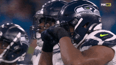 a group of football players wearing seahawks helmets are watching a game on fox nfl