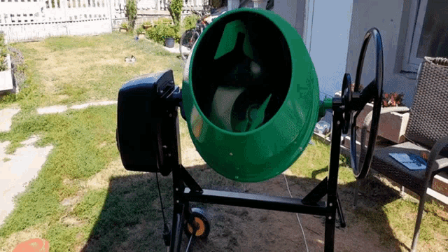 a green concrete mixer is sitting in a yard
