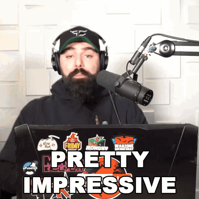 a man wearing headphones and a hat stands in front of a microphone with the words pretty impressive above him