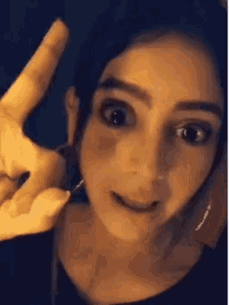a close up of a woman making a peace sign with her hand