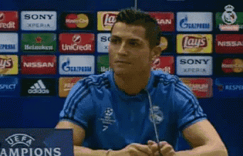 a man in a blue shirt is sitting in front of a sign that says champions