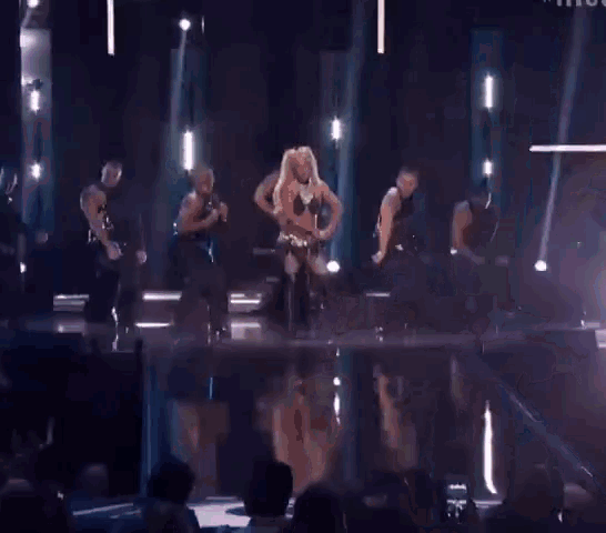a woman is dancing on a stage in front of a crowd of people .