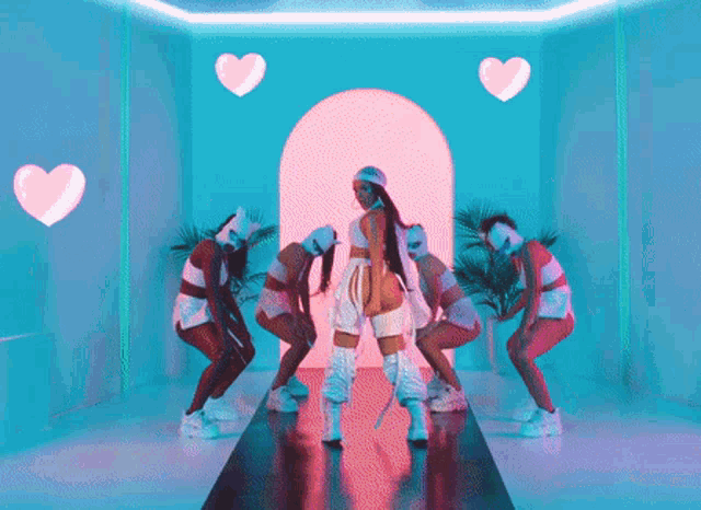 a woman is standing on a runway surrounded by dancers and pink hearts