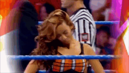 a woman in a plaid top is standing in a wrestling ring .