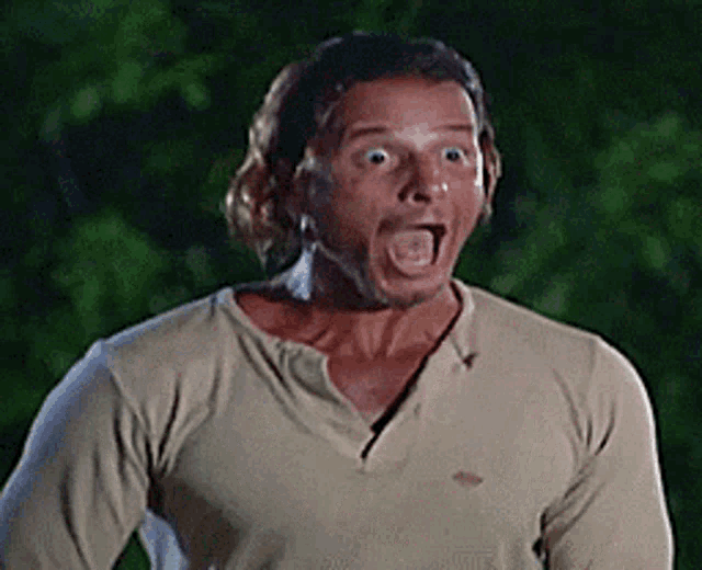 a man wearing a tan shirt is making a surprised face