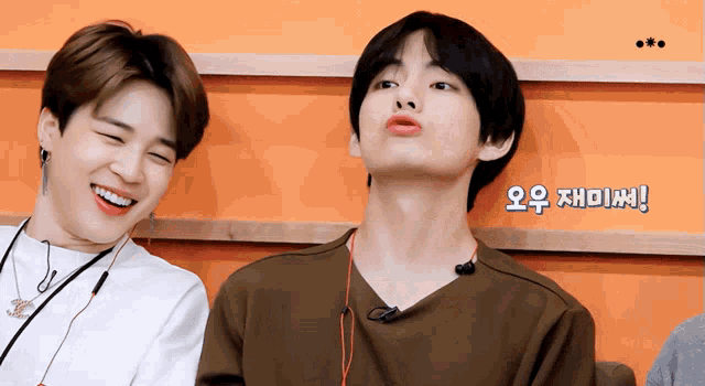 two young men are sitting next to each other and one of them is wearing earbuds