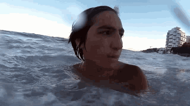 a man is swimming in the ocean and looking at the camera