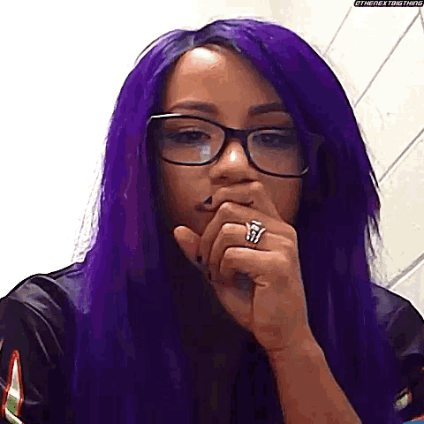 a woman with purple hair and glasses is covering her mouth .