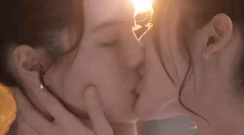 two women are kissing each other in front of a light bulb