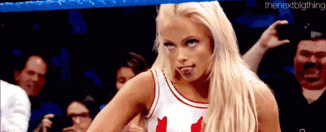 a woman is sticking her tongue out while wearing a canadian flag tank top .