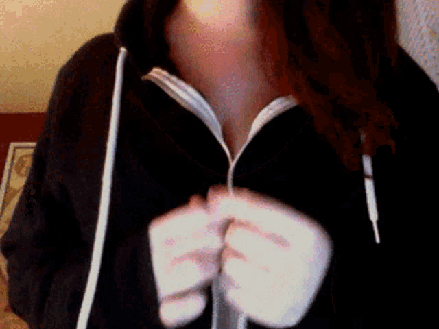 a woman wearing a black hoodie has her breasts visible