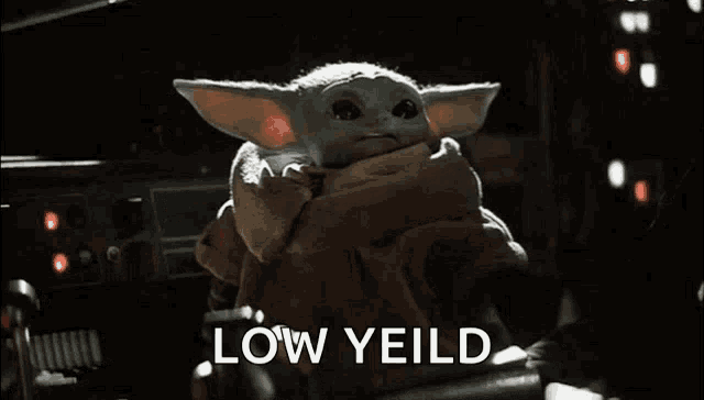 a baby yoda from the mandalorian is standing in a dark room with the words `` low yield '' written on the screen .