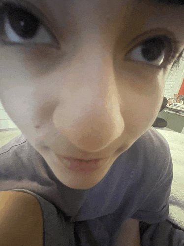a close up of a girl 's face with a purple shirt on