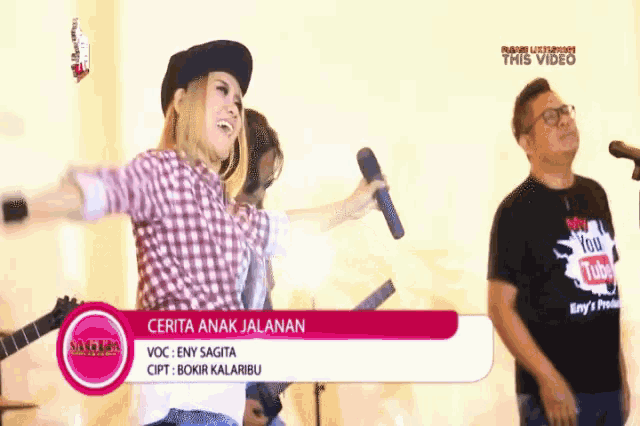 a woman sings into a microphone while a man plays a guitar behind her
