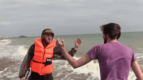a man wearing a life vest that says hh on it is giving another man a high five