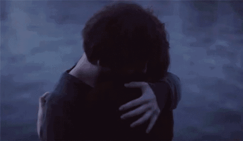 a man and a woman are hugging each other in front of the ocean .