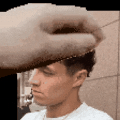 a close up of a man 's face with a hand on his head .