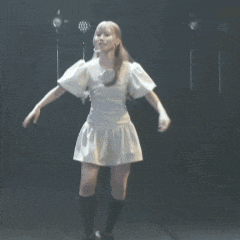 a woman in a white dress is dancing on a stage with her skirt blowing in the wind .